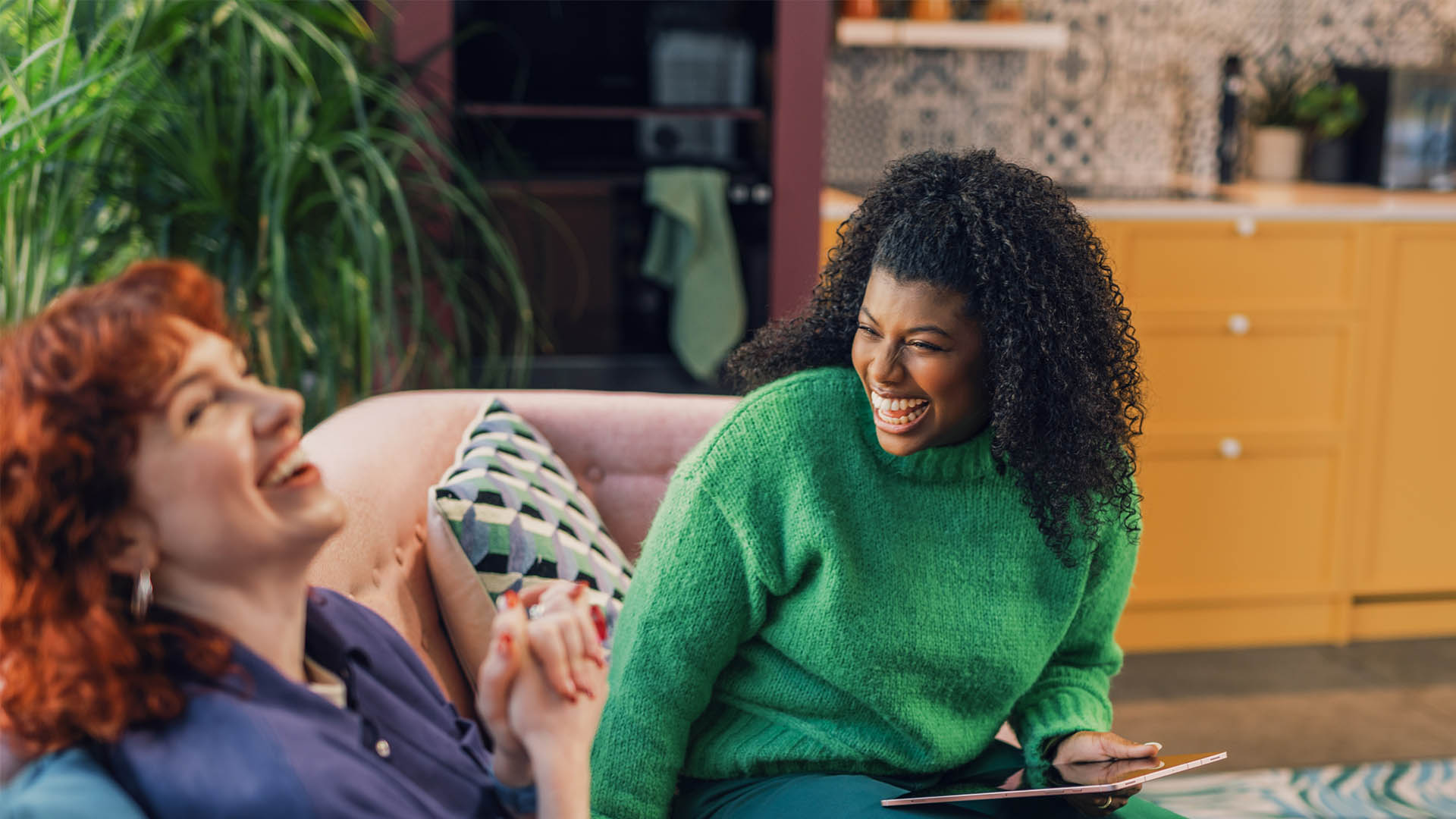 Friends laughing together on couch.